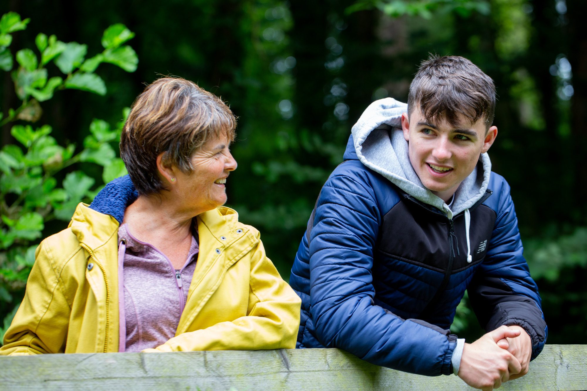 Foster carer and boy smiling at a fence