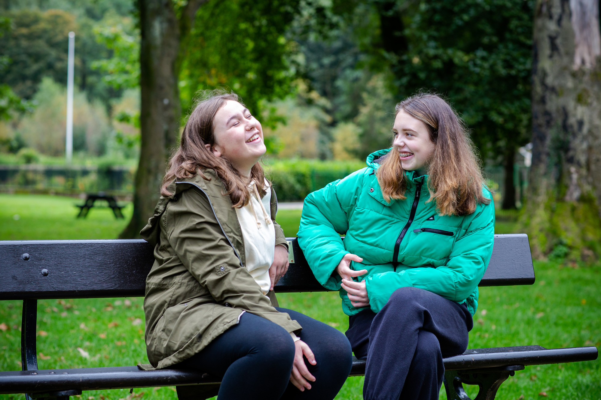 two young girls laughing on a park bench