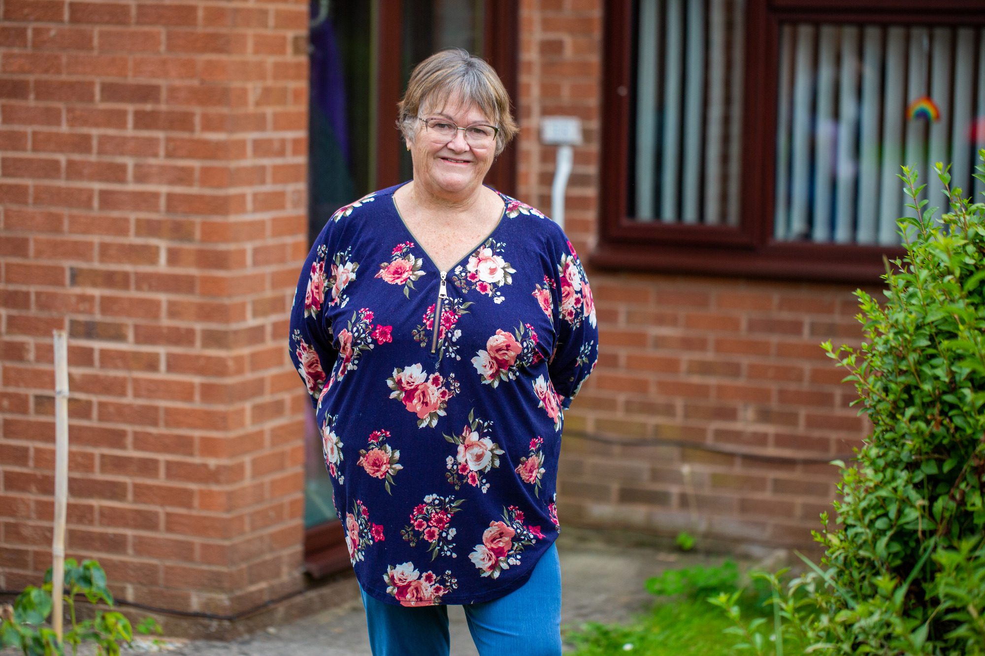 carer smiling in front of her house