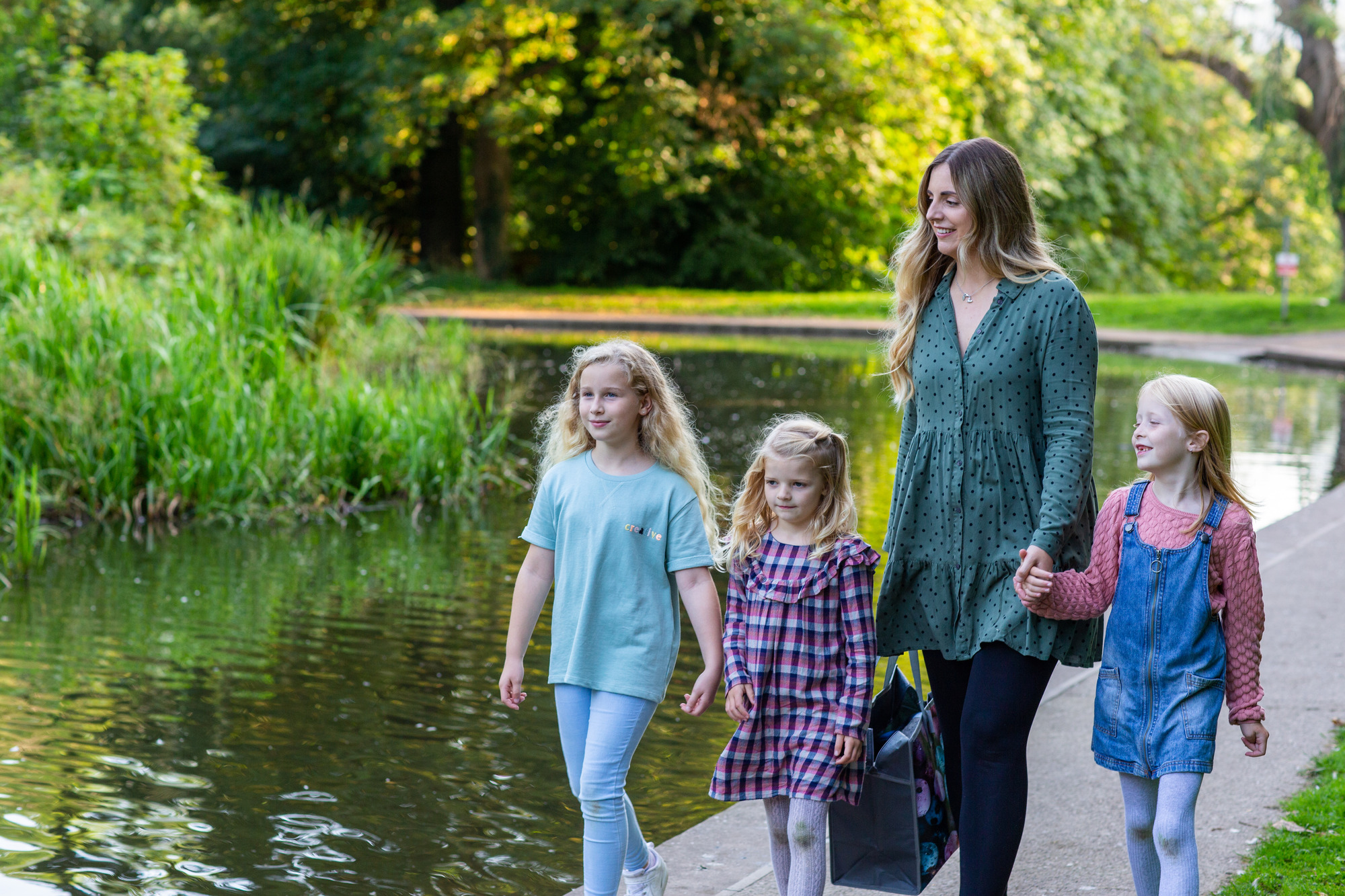woman and three young girls walking alongside a river